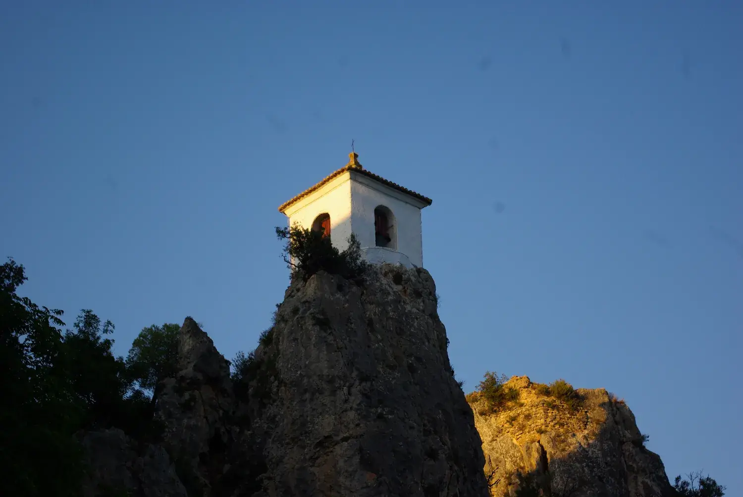 Guadalest’s white bell tower on top of a rocky pinnacle at sunset