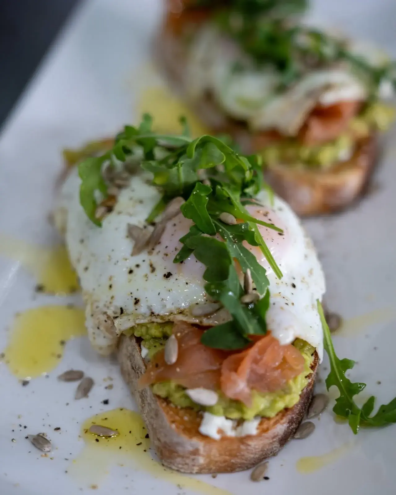 Tostada met avocado, gerookte zalm, spiegelei, rucola en zonnebloempitten bij Hola Patatas