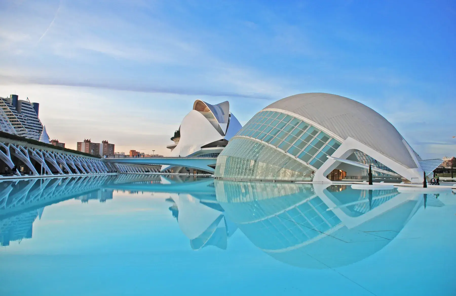The Hemisfèric at the City of Arts and Sciences reflected in a pool under a blue sky
