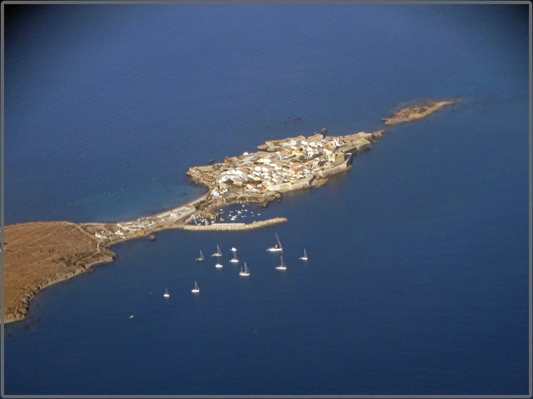 Aerial view of the narrow, flat island of Tabarca surrounded by deep blue water