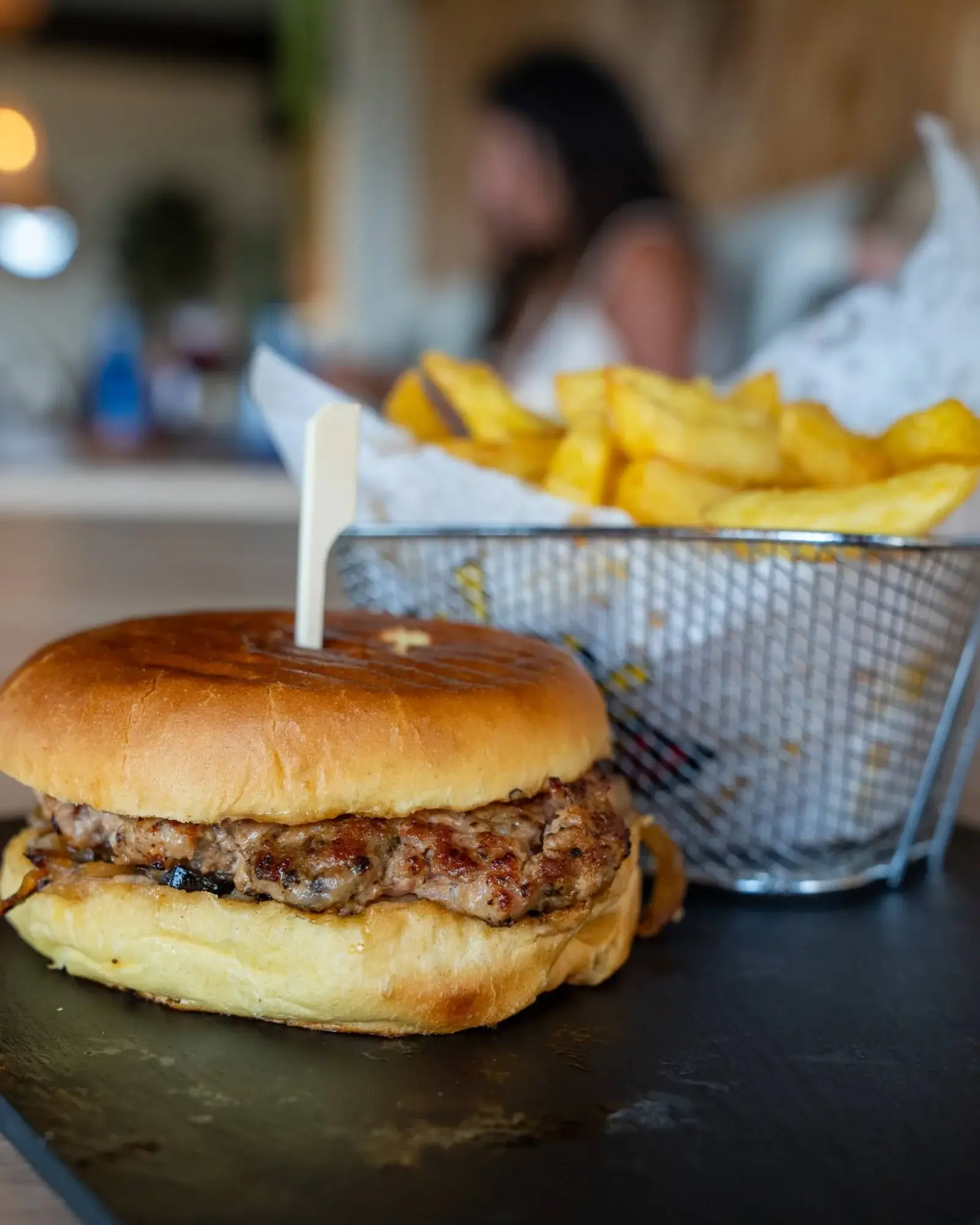 Burger in a toasted brioche bun and a basket of golden Belgian fries at Hola Patatas in Ciudad Quesada